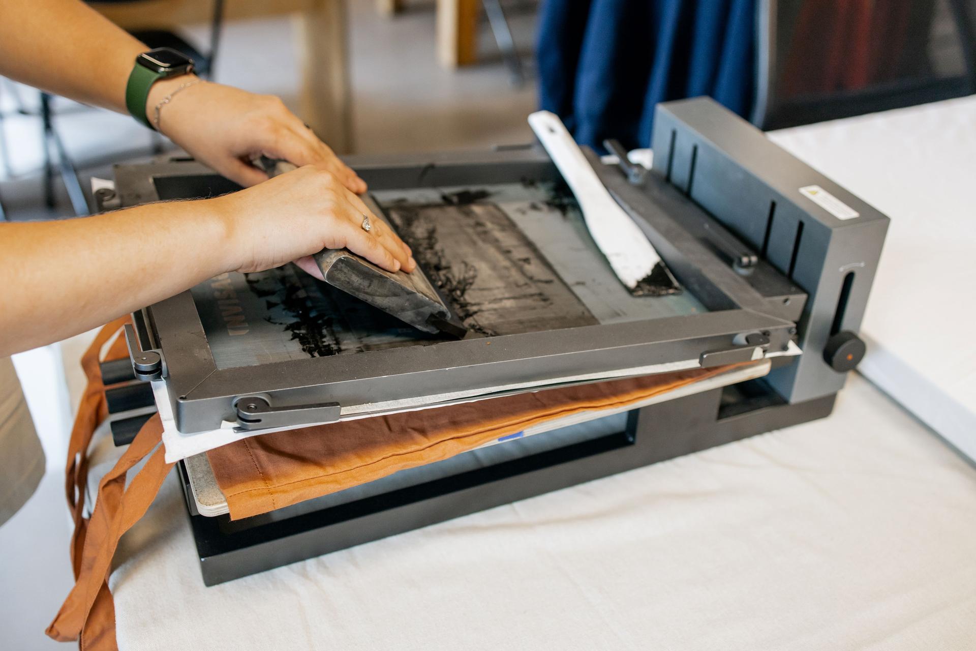 Manual Silk Screen Printing on Fabric – Close-up of Hands Working with Screen Printing Machine in Workshop