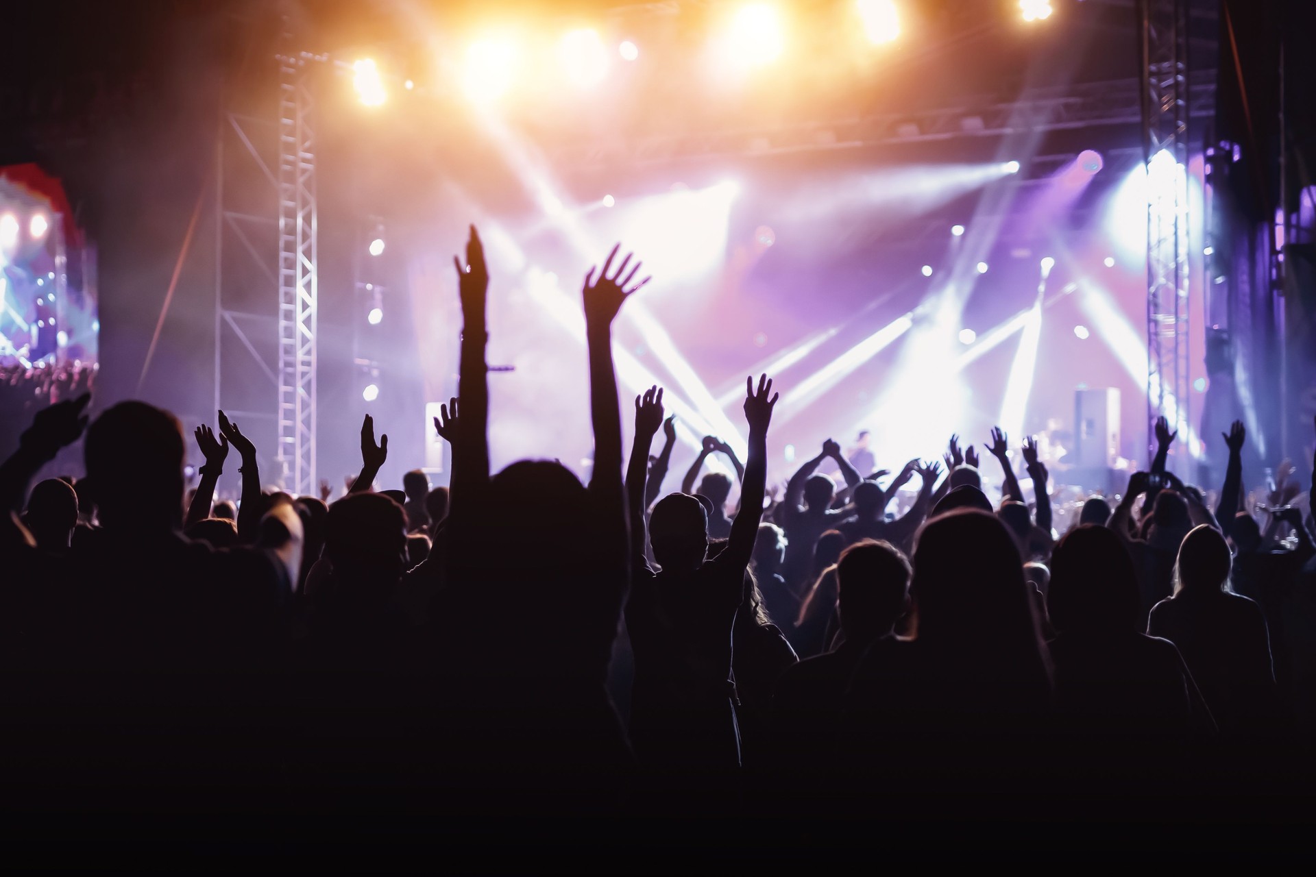 Rock concert, cheering crowd in front of bright colorful stage lights