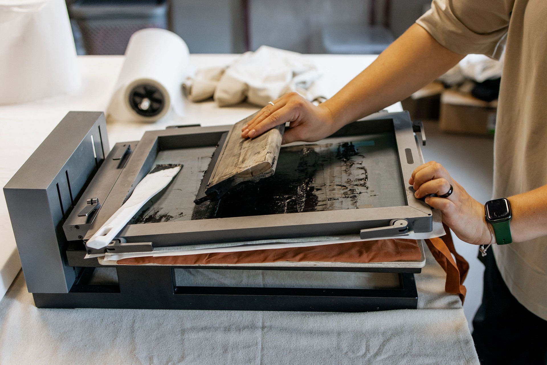 Manual Silk Screen Printing on Fabric – Close-up of Hands Working with Screen Printing Machine in Workshop