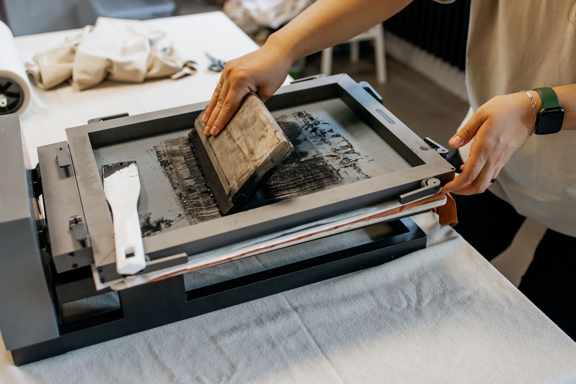 Manual Silk Screen Printing on Fabric – Close-up of Hands Working with Screen Printing Machine in Workshop