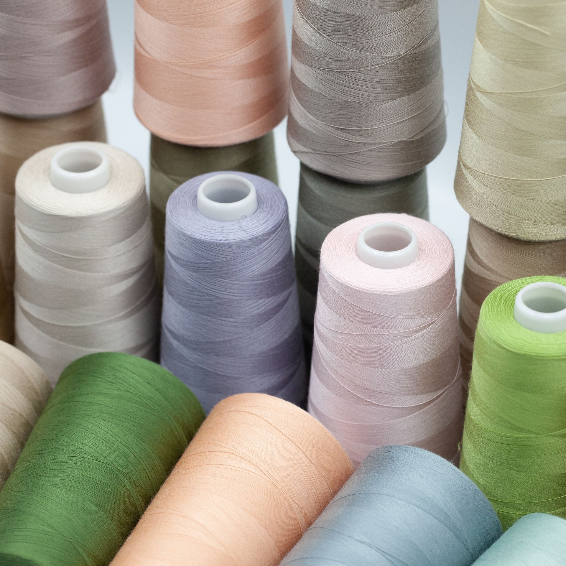 Thread spools background. Various colors sewing kit. Collection of threads. Pale pastel colors.
